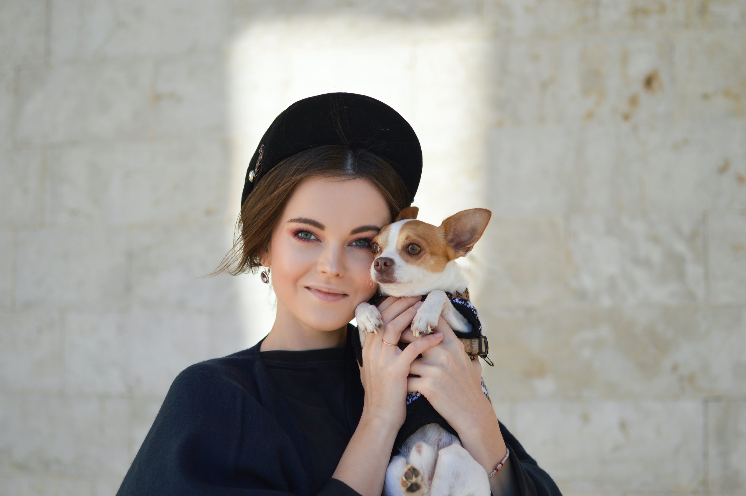 young lady with black baseball cap holding small dog
